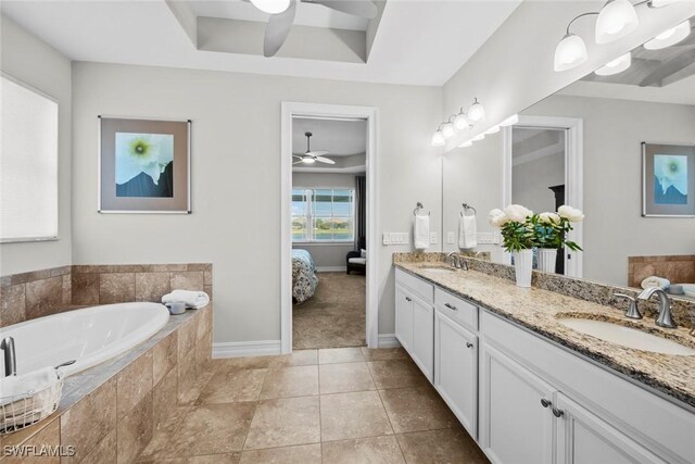 bathroom featuring tile patterned floors, vanity, a raised ceiling, ceiling fan, and tiled bath