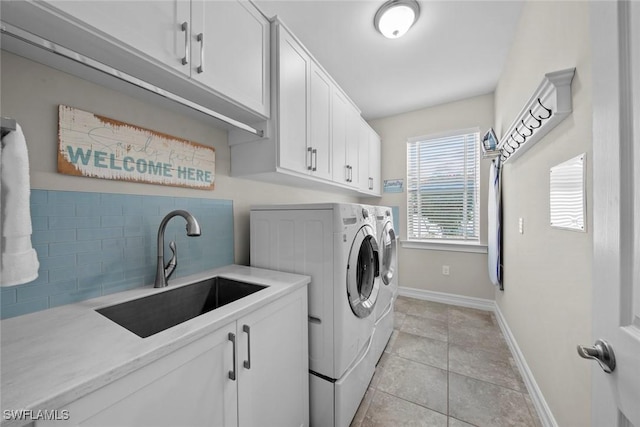 laundry room featuring cabinets, light tile patterned floors, separate washer and dryer, and sink