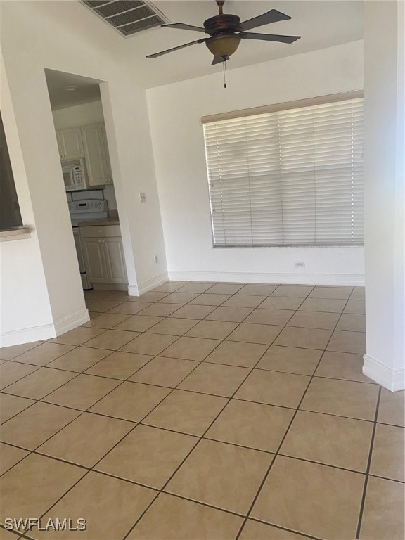 empty room featuring ceiling fan, light tile patterned flooring, and vaulted ceiling