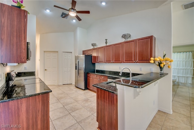 kitchen featuring kitchen peninsula, light tile patterned floors, dark stone counters, and appliances with stainless steel finishes