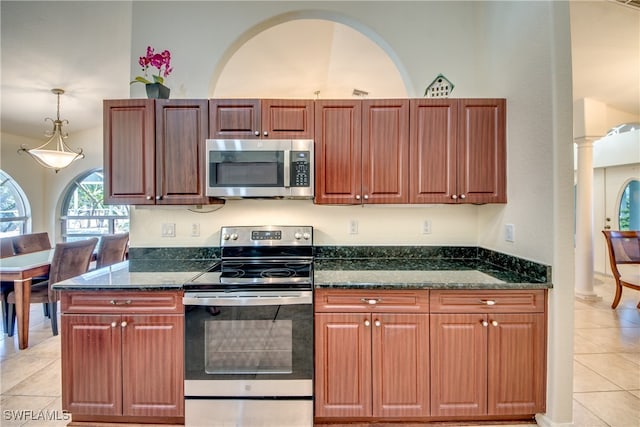 kitchen featuring light tile patterned flooring, dark stone countertops, stainless steel appliances, and decorative columns