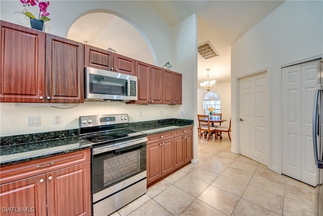 kitchen with high vaulted ceiling, a notable chandelier, dark stone countertops, light tile patterned floors, and appliances with stainless steel finishes