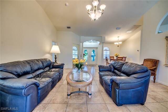 tiled living room featuring ornate columns, french doors, and an inviting chandelier