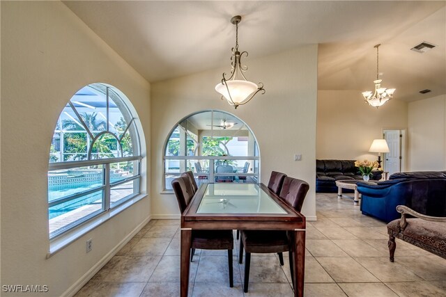 dining area with light tile patterned floors, an inviting chandelier, and lofted ceiling