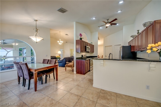 interior space featuring stainless steel appliances, kitchen peninsula, pendant lighting, light tile patterned flooring, and ceiling fan with notable chandelier