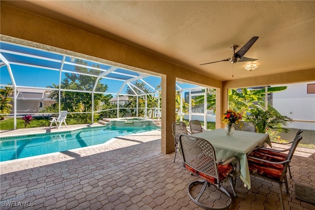 view of swimming pool featuring ceiling fan, glass enclosure, an in ground hot tub, and a patio