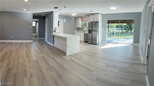 kitchen featuring pendant lighting, light hardwood / wood-style flooring, white cabinets, and stainless steel appliances