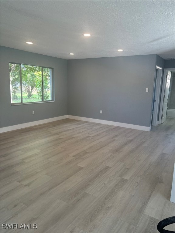 spare room featuring a textured ceiling and light wood-type flooring