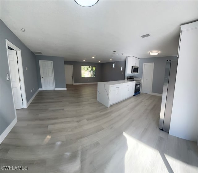 kitchen with white cabinets, light wood-type flooring, and range with electric cooktop