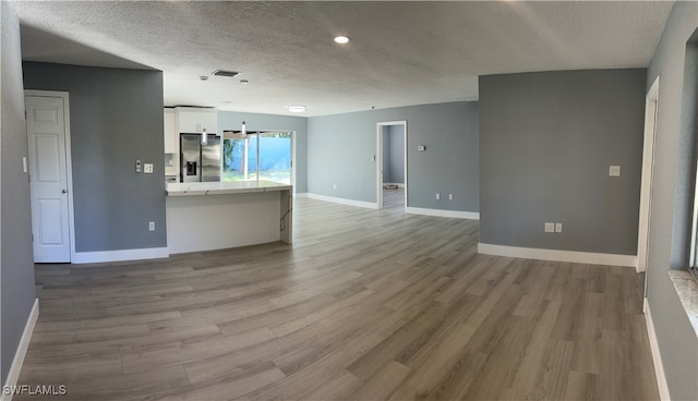 unfurnished living room with hardwood / wood-style floors and a textured ceiling