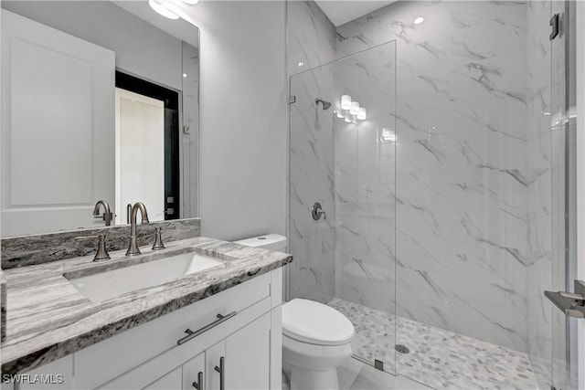 bathroom featuring vanity, toilet, and a tile shower