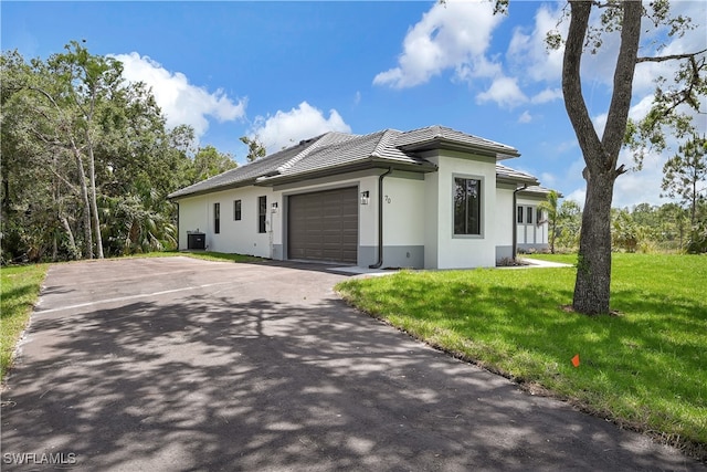 view of front of house with a garage, central air condition unit, and a front lawn