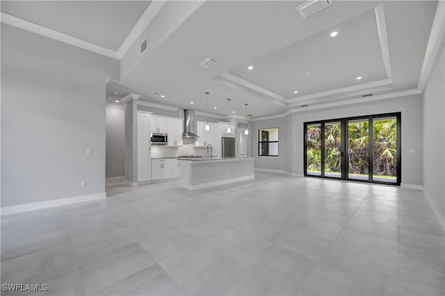 unfurnished living room featuring french doors, a raised ceiling, crown molding, and sink