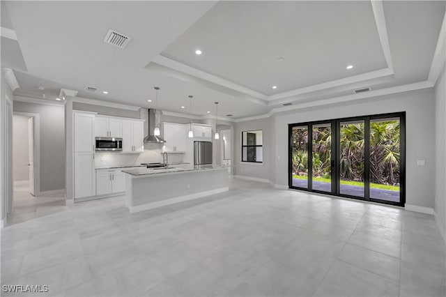 unfurnished living room featuring a raised ceiling, crown molding, and sink