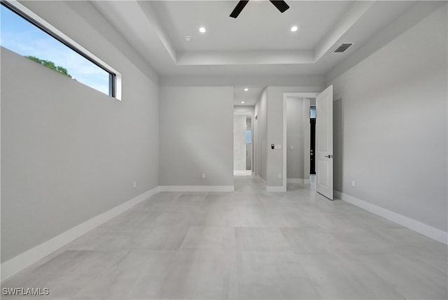 spare room with ceiling fan and a tray ceiling