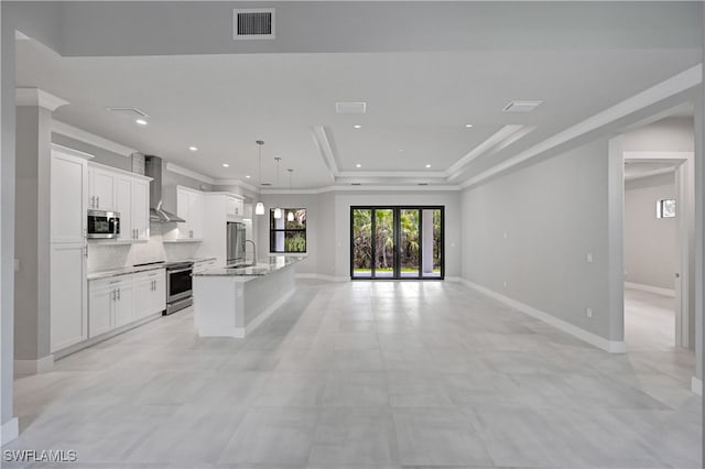 kitchen with white cabinets, pendant lighting, stainless steel appliances, and a center island with sink