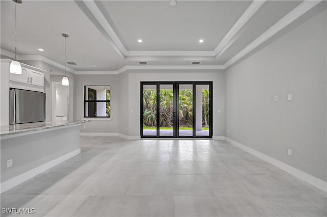 unfurnished living room with ornamental molding, a tray ceiling, and french doors