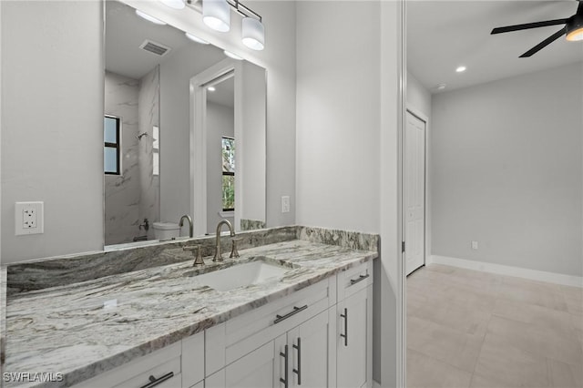 bathroom featuring ceiling fan, vanity, toilet, and a tile shower