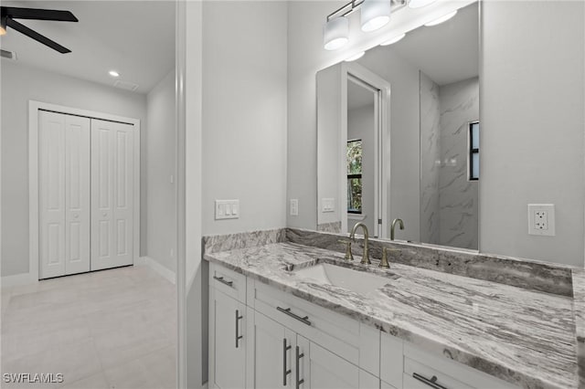 bathroom with ceiling fan, vanity, and tiled shower