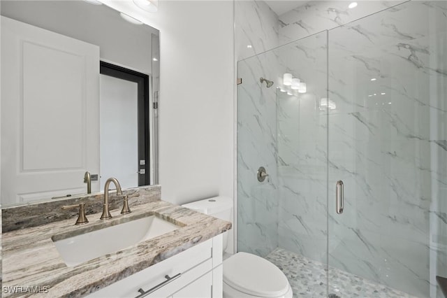 bathroom featuring vanity, a shower with shower door, and toilet