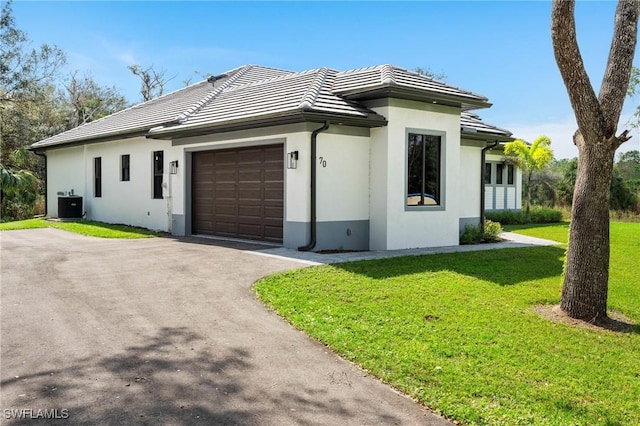 view of front facade featuring a garage, cooling unit, and a front lawn