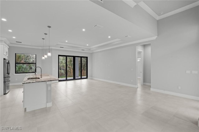 kitchen with sink, stainless steel refrigerator, a kitchen island with sink, white cabinetry, and decorative light fixtures