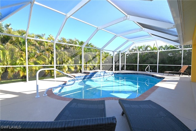 view of pool with glass enclosure and a patio