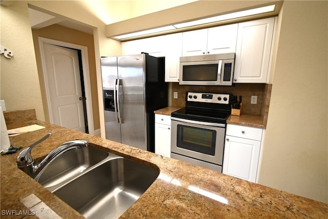 kitchen with decorative backsplash, light stone counters, stainless steel appliances, sink, and white cabinetry