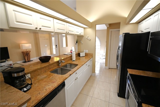 kitchen with sink, light tile patterned floors, light stone countertops, appliances with stainless steel finishes, and white cabinetry