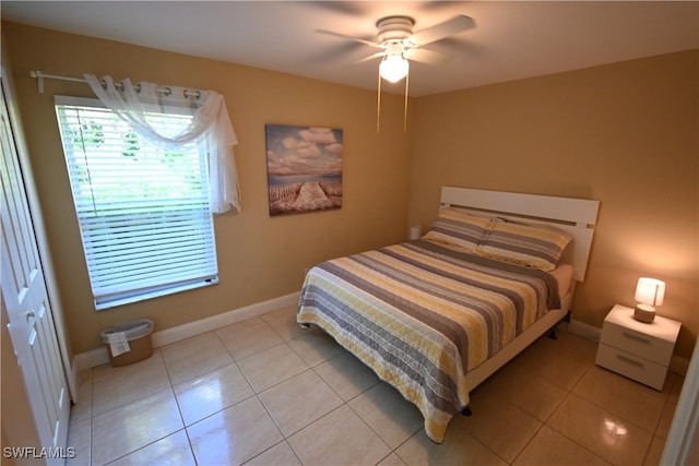 bedroom with ceiling fan, light tile patterned floors, and a closet