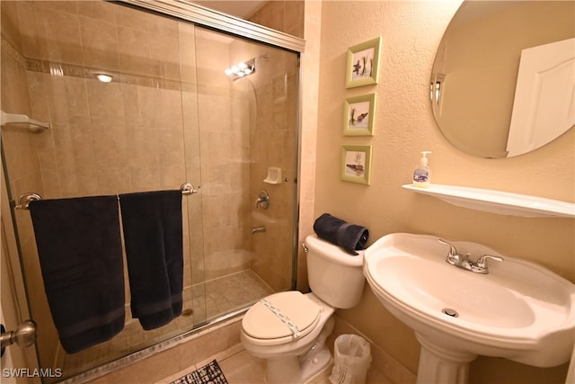 bathroom featuring sink, an enclosed shower, and toilet