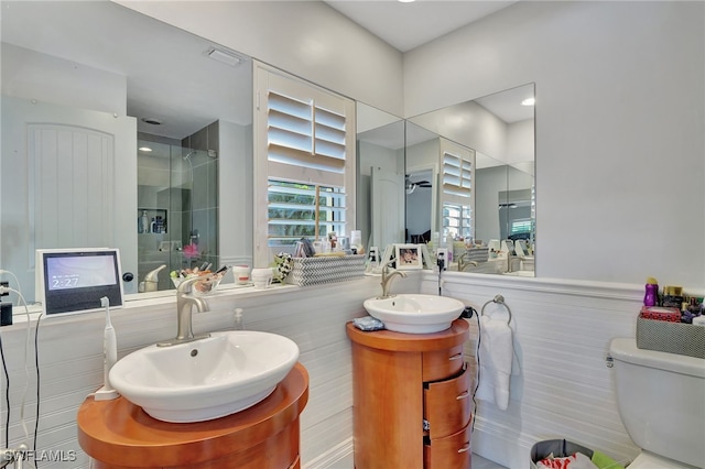 bathroom with tiled shower, vanity, toilet, and ceiling fan