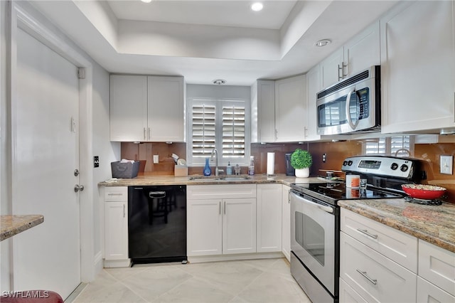 kitchen with a tray ceiling, white cabinetry, sink, and stainless steel appliances