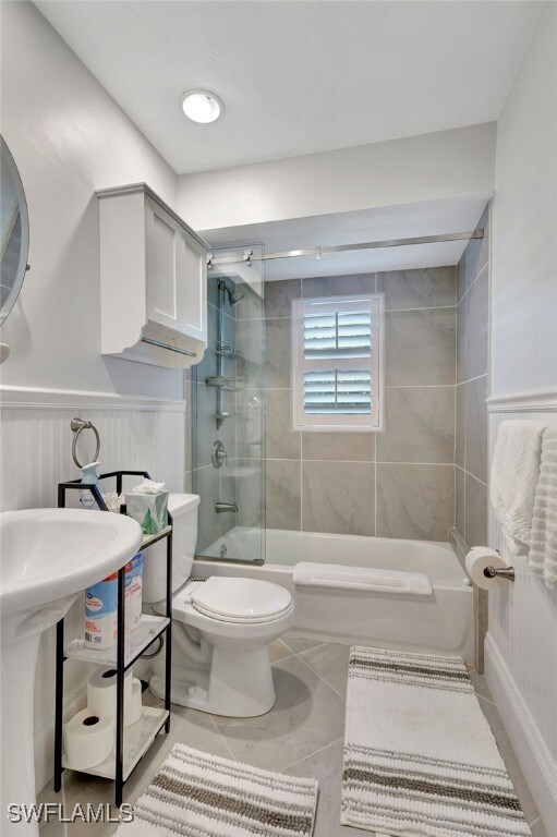 full bathroom with shower / bath combination with glass door, tile patterned floors, sink, and toilet