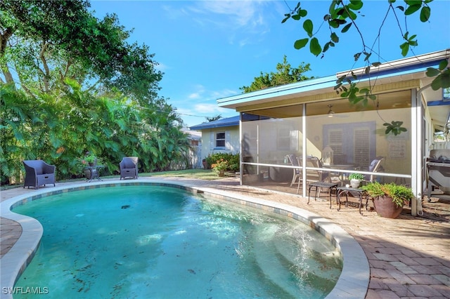 view of swimming pool with a sunroom and a patio