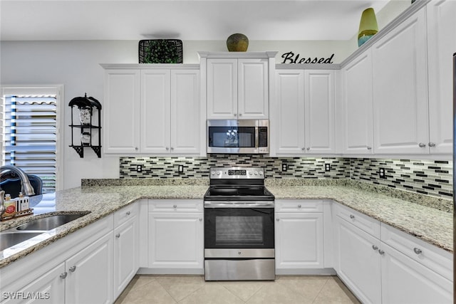 kitchen with backsplash, light stone countertops, white cabinets, and stainless steel appliances