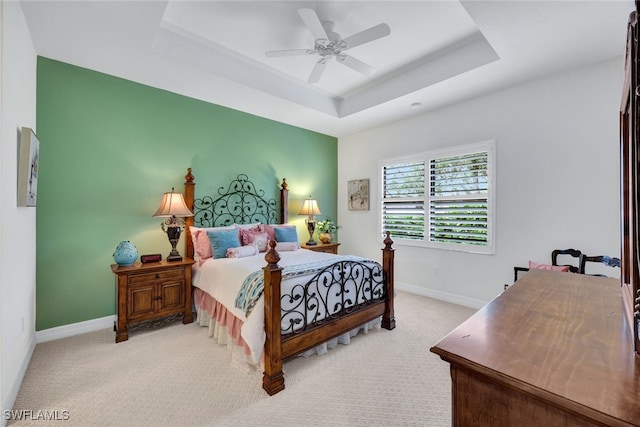 bedroom with light carpet, a raised ceiling, and ceiling fan