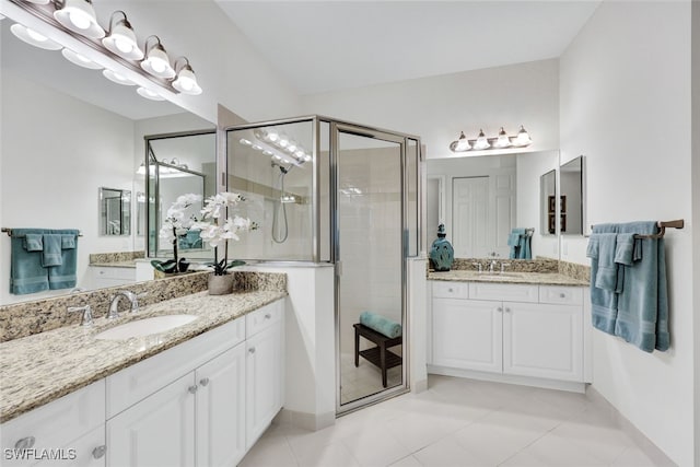 bathroom with a shower with door, vanity, and tile patterned flooring