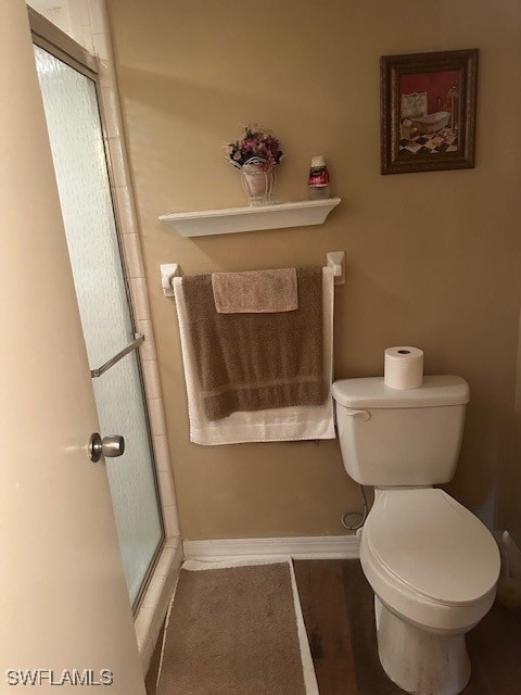 bathroom featuring toilet and a shower with door