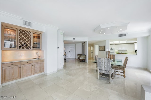 dining room with light tile patterned floors, wet bar, and ornamental molding