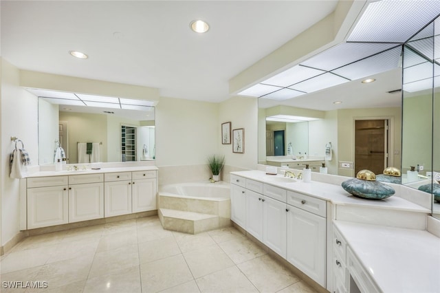 bathroom with tile patterned floors, vanity, and a relaxing tiled tub