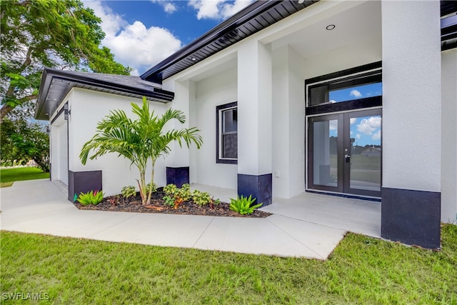 view of exterior entry with a yard and french doors