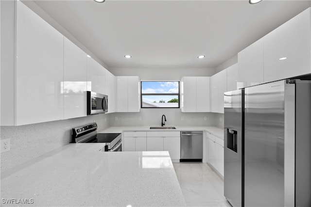 kitchen featuring decorative backsplash, sink, white cabinets, and appliances with stainless steel finishes