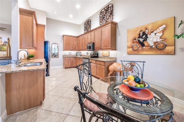 kitchen with light stone countertops, light tile patterned floors, stainless steel appliances, and sink