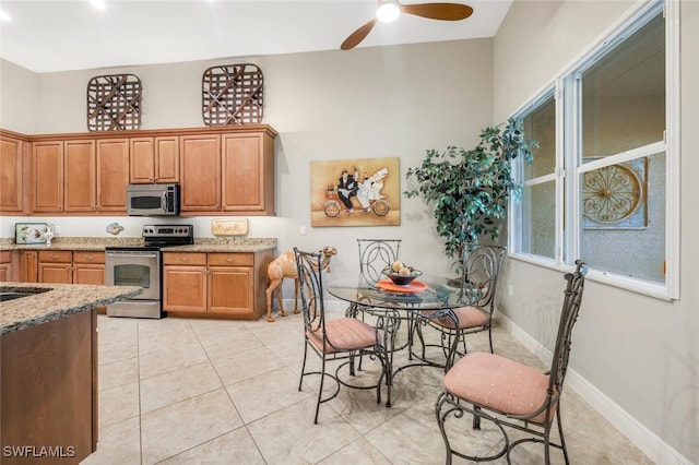 kitchen featuring light stone countertops, stainless steel appliances, ceiling fan, and light tile patterned flooring