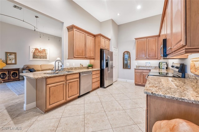 kitchen featuring light stone countertops, sink, stainless steel appliances, kitchen peninsula, and light tile patterned floors