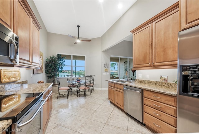 kitchen featuring ceiling fan, light tile patterned flooring, light stone counters, and appliances with stainless steel finishes