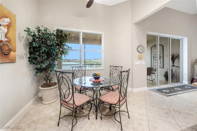 tiled dining space featuring ceiling fan and a water view