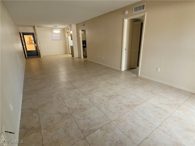 empty room with ceiling fan and a textured ceiling