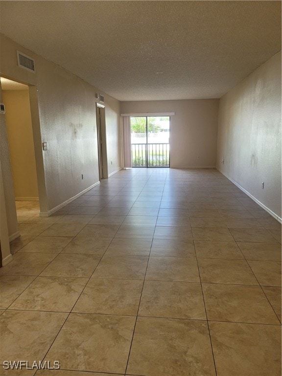 tiled empty room with a textured ceiling